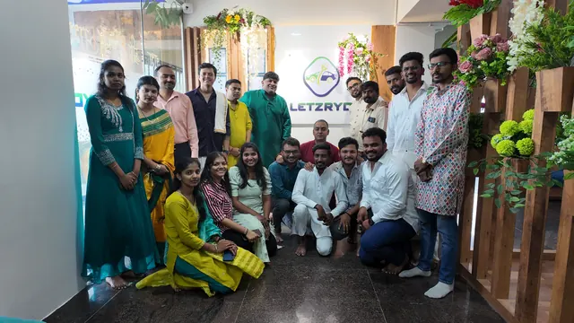 Team in festive attire in front of the LetzRyd logo wall